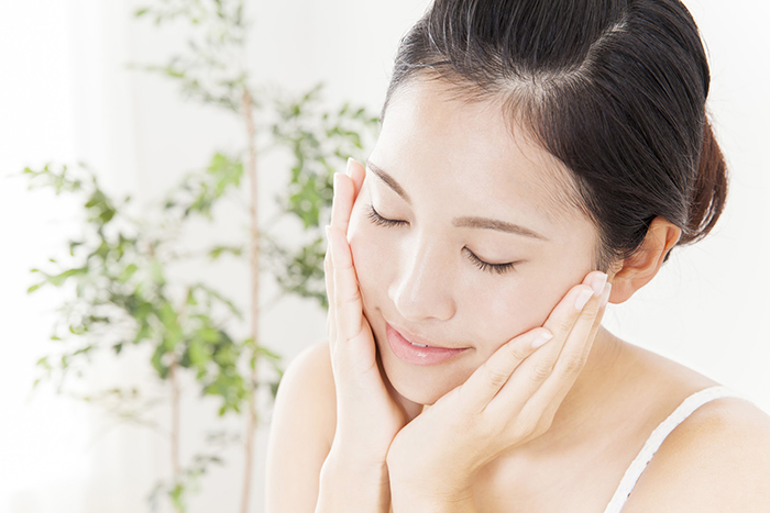 両手を頬に添えてほほ笑む女性